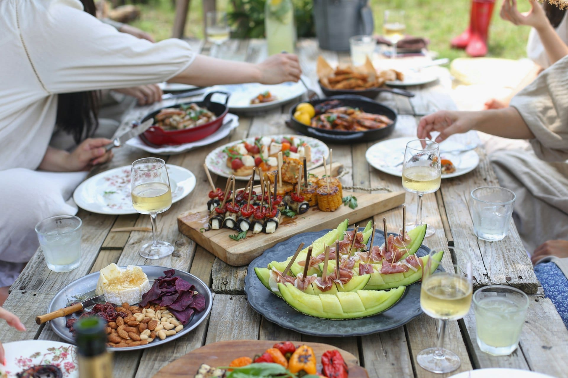 Friends sharing a spread of food at an outdoor picnic table